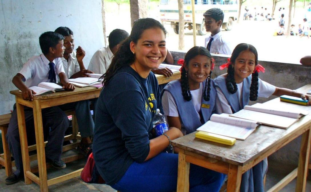 Projects Abroad volunteer and two students practice their English reading in India. Teaching volunteer helps her students with an English reading exercise during class in India.